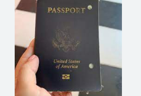 A handheld old passport punctured by two holes